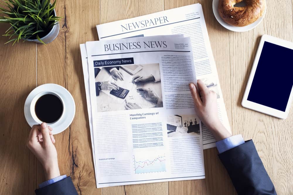 CFO FACTORY training IMA accredited Egypt Middle East – Professional engaged in morning routine reading business news with coffee and smartphone at desk – Become a transformative leader in finance