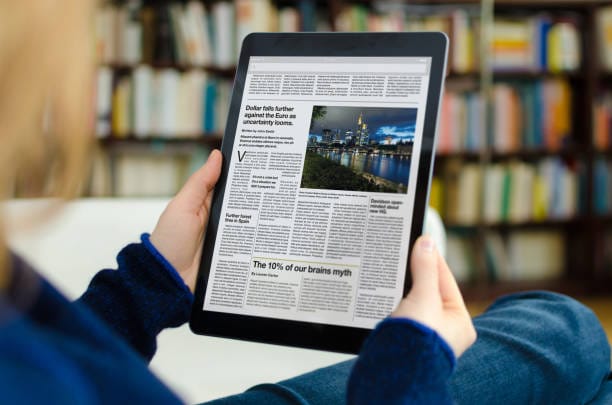 CFO FACTORY training IMA accredited Egypt Middle East – A person reads finance news on a tablet featuring articles and images in a cozy library setting – Become a transformative leader in finance