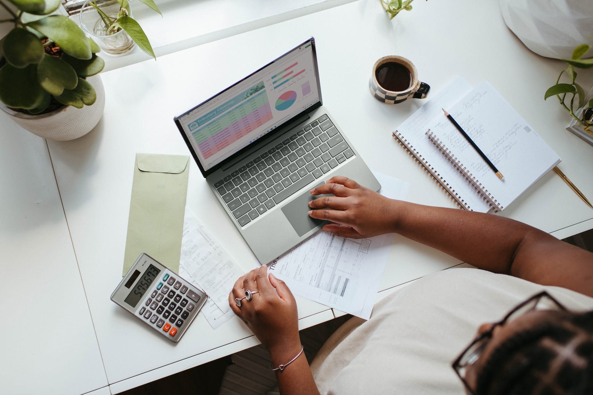 CFO FACTORY training, IMA accredited, Egypt, Middle East – Person working on financial reports with a laptop and calculator on desk – Become a transformative leader in finance